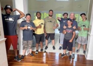 Group of smiling Moving Solutions staff members posing together in a bright, spacious room, showcasing teamwork and professionalism in moving services.